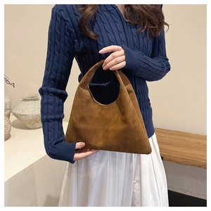 Close-up of brown suede tote bag carried by model in a cozy knit sweater