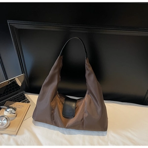 Close-up of coffee brown nylon hobo bag with black leather strap and brand logo detail