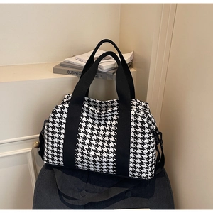Close-up of houndstooth travel bag showing woven fabric texture and black straps
