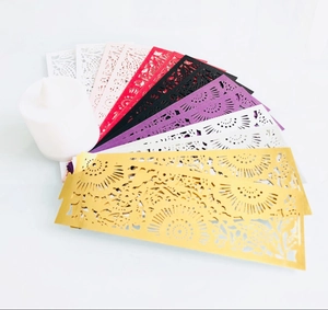 Detailed laser-cut paper candle wraps with intricate floral patterns in multiple colors