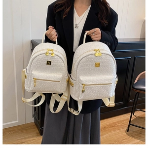 Detailed view of white tweed backpack featuring textured weave and gold-tone metal hardware