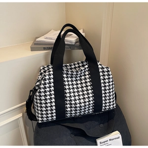 Detailed shot of houndstooth travel bag with reinforced canvas handles and shoulder strap