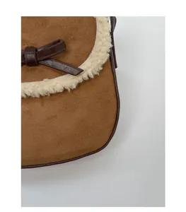 Détail du sac en daim marron avec bordure en similicuir blanc et nœud décoratif chic