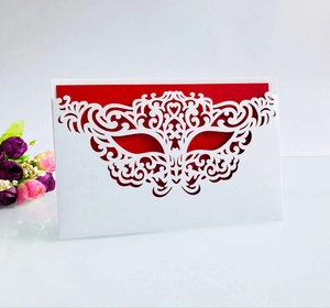 Macro detail of laser-cut mask design on white wedding invitation with red insert card