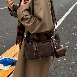 Detail view of dark coffee suede crossbody bag with silver studs and mini coin purse charm