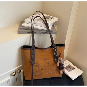 Detail of brown suede tote bag with cartoon cat embroidery and cute bunny charm