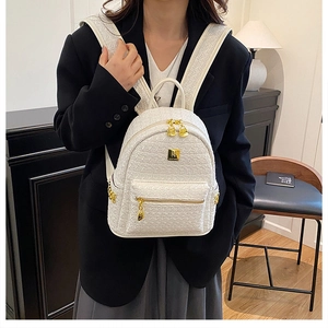 Detail of white tweed texture and polished gold logo on a stylish small backpack