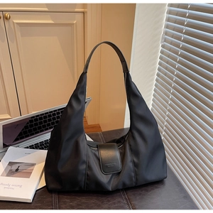 Detail of black nylon crescent shoulder bag on leather desk with urban shadows