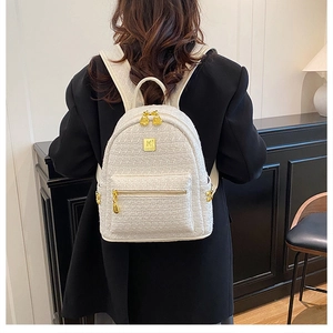 Detailed back view of a white tweed mini backpack with gold hardware worn on a black blazer