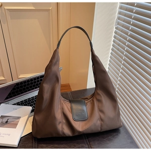 Close-up of large brown hobo bag showing high-density nylon fabric and leather buckle detail