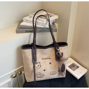 Detail of beige faux suede tote bag featuring cat embroidery and a cute bunny charm