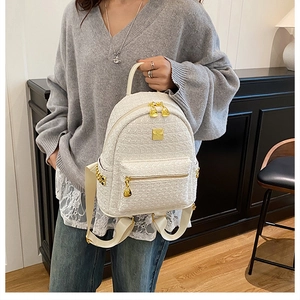 Close-up of white tweed backpack featuring woven texture and gold metallic hardware details