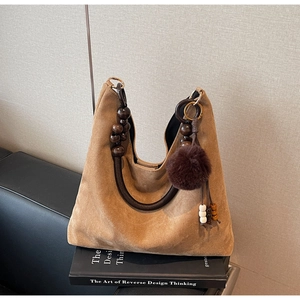 Détail du sac cabas en daim marron avec poignée en perles de bois et breloque pompon chic