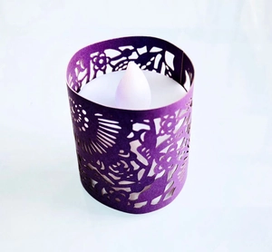 Macro shot of purple laser-cut lace candle sleeve with white LED tea light inside