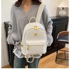 Detail view of cream tweed backpack with gold zipper and stud accents on model