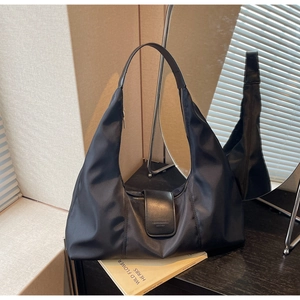 Close-up of black nylon hobo bag with leather flap and zipper on black wooden table