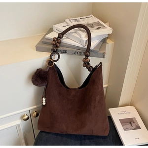 Détail du sac cabas en daim marron avec poignée en perles de bois et breloque en peluche