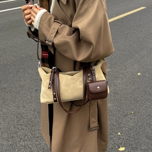Detail of beige suede tote bag with brown leather handles and mini pouch accessory