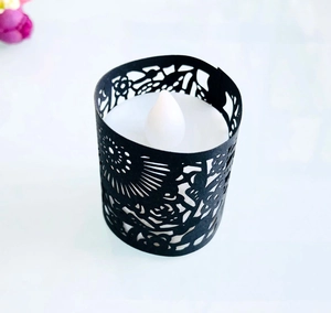 Detailed view of white LED tea light with black laser-cut hollow pattern sleeve