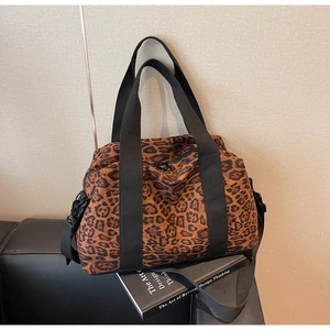 Detail of leopard print travel bag featuring wide black webbing handles and sturdy canvas