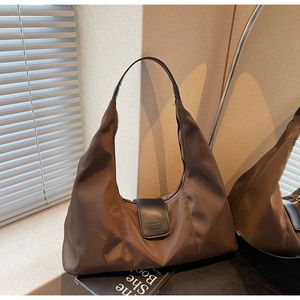 Close-up of dark brown nylon hobo bag with black leather strap and magnetic flap buckle