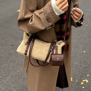 Detail view of khaki suede tote bag with brown leather strap and metal rivet accents