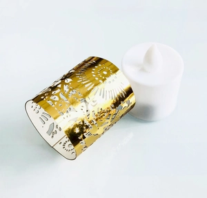 Detail of golden laser-cut paper sleeve and LED flameless candle for festive party decor