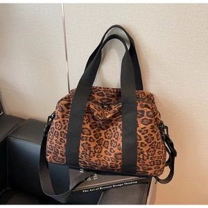 Detail of leopard print travel bag with sturdy black handles and adjustable shoulder strap