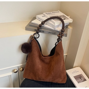 Détail du sac hobo en daim marron avec poignée en perles de bois et breloque en peluche
