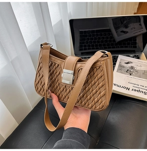 Detail of tan woven leather texture and silver buckle on a modern baguette shoulder bag
