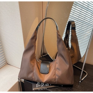 Detailed close-up of brown nylon hobo bag with leather buckle and metallic zipper