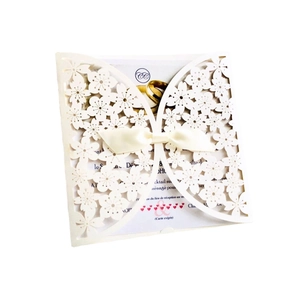 Macro view of laser-cut cherry blossom wedding invitation with cream satin ribbon bow