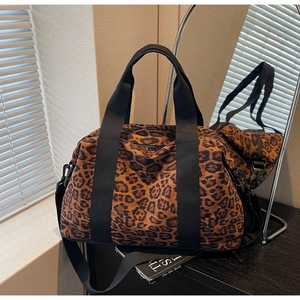 Detail of leopard print travel bag featuring sturdy nylon straps and metal hardware hooks