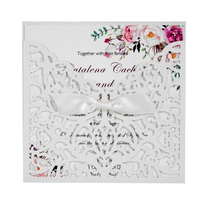 Détail de la dentelle florale découpée au laser et nœud en satin blanc sur l'invitation