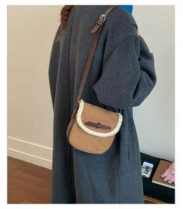 Gros plan du sac besace en daim marron avec bordure en laine blanche et petit nœud