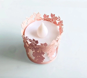 Detail view of laser-cut grape vine paper sleeve with LED tea light candle