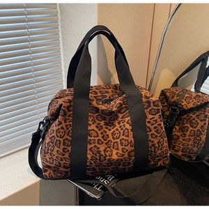 Detail of leopard print travel bag with sturdy black handles and adjustable shoulder strap