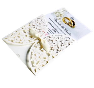 Detailed laser-cut floral wedding invitation with cream silk ribbon and elegant paper texture