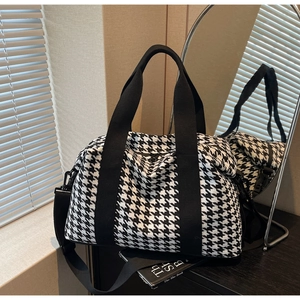 Close-up of houndstooth travel bag with wide webbing handles and detachable shoulder strap