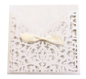 Détail macro du motif dentelle découpé au laser et nœud en satin sur invitation blanche