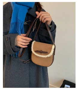 Détail d'un sac besace en daim marron avec bordure en polaire blanche et nœud en cuir