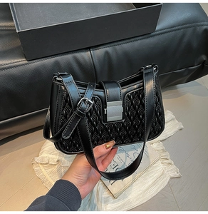 Close-up of black crossbody bag showing woven leather texture and silver metal buckle
