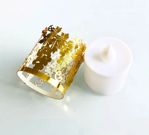 Detail of golden laser-cut grape pattern paper lampshade with a white LED tealight candle