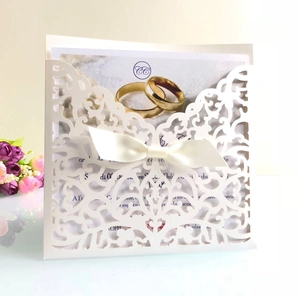 Détail d'invitation de mariage ivoire découpée au laser avec nœud et motifs dorés