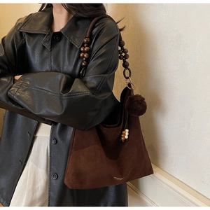 Vue détaillée du sac cabas en daim marron avec bandoulière en perles de bois et pompon