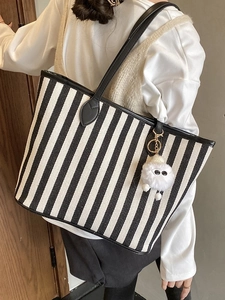 Classic black and white striped canvas tote bag with leather handles and fuzzy charm