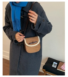 Détail du sac bandoulière marron avec bordure en peau de mouton et nœud en cuir élégant