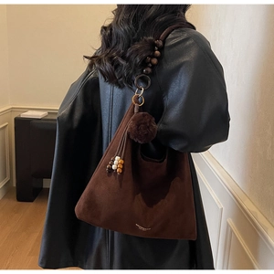 Détail du sac cabas en daim marron foncé avec perles en bois et pendentif pompon peluche