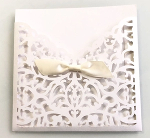 Détail d'invitation de mariage ivoire découpée au laser avec dentelle et nœud en satin