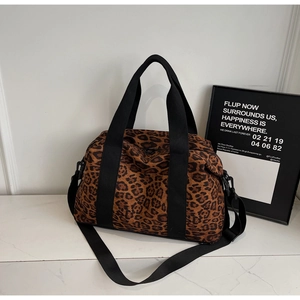 Detail view of large leopard print travel bag with reinforced black nylon handles and straps